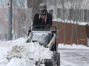 Snow is cleared on the sidewalks along 5th Avenue and 3rd Street S.E. during a cold afternoon in Calgary. Friday, February 5, 2021.