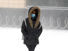 A pedestrian crosses the road along 6th Avenue and 3rd Street S.E. during a cold afternoon in Calgary. Friday, February 5, 2021.