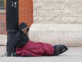 A homeless man tries to stay warm on the corner of 17th Avenue and 7th Street S.W. in downtown Calgary on Jan. 25, 2021.