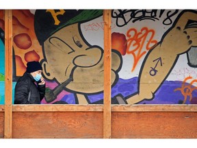 Masked Calgarians pass a mural of Popeye at the West Village construction site in downtown Calgary on Wednesday, Jan. 6, 2021.