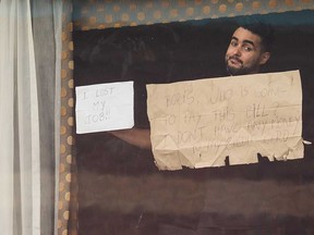 A man holds up signs reading "I LOST MY JOB!!" and "BORIS, WHO IS GOING TO PAY THIS BILL? I DON'T HAVE ANY MONEY TO PAY MY CREDIT CARD" at the window of his hotel room in London, England. Beginning in mid-February, people arriving from 33 "red list" countries, including South Africa and the United Arab Emirates, must isolate in hotels rooms for 10 days at their own expense.