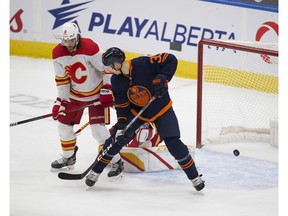 The Edmonton Oilers’ Connor McDavid (not pictured) scores as teammate Alex Chiasson and the Calgary Flames’ Juuso Valimaki watch the puck go past goalie Jacob Markstrom at Rogers Place in Edmonton on Saturday, Feb. 20, 2021.