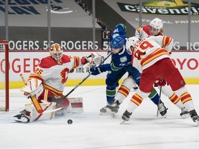 Calgary Flames defencemen Juuso Valimaki and Nikita Nesterov (No. 89) check Vancouver Canucks forward Tanner Pearson as goalie Jacob Markstrom makes a save at Rogers Arena in Vancouver on Thursday, Feb. 11, 2021.