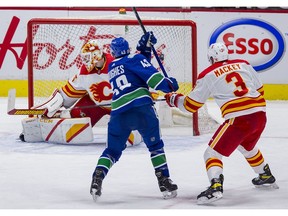 Vancouver Canucks defenceman Quinn Hughes scores on Calgary Flames goalie Jacob Markstrom as Calgary defenceman Connor Mackey looks on in the second period at Rogers Arena on Saturday night. Markstrom turned aside 43 shots in the loss.