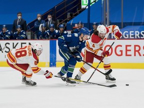 Calgary Flames forward Andrew Mangiapane (88) and defenceman Rasmus Andersson check Vancouver Canucks forward Elias Pettersson at Rogers Arena in Vancouver on Monday, Feb. 15, 2021.