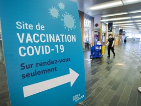 A cleaner walks through the empty halls of one of the mass COVID-19 vaccination sites as the wait for more doses to arrive continues Tuesday, Feb. 9, 2021, in Montreal.