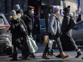 People wear face masks as they walk along a street in Montreal, Sunday, Feb. 21, 2021.