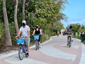 Tourists wearing masks bike along the beach in Miami, Florida, on Dec. 20, 2020, amid the COVID-19 pandemic.