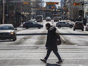 A pedestrian crosses a street in downtown Calgary on a sunny day on Thursday, March 4, 2021.
