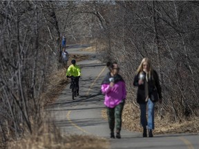 People spend the sunny afternoon on the Elbow River pathway in Stanley Park on Saturday, March 20, 2021.