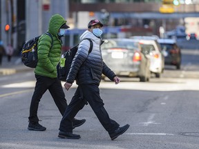 Masked pedestrians cross a street in downtown Calgary on Tuesday, March 23, 2021.