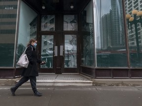 A masked pedestrian walks in downtown Calgary on Friday, March 26, 2021.