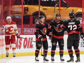 OTTAWA, ON - MARCH 1:  Evgenii Dadonov #63 of the Ottawa Senators celebrates his third period goal with teammates Thomas Chabot #72 and Colin White #36 as Nikita Nesterov #89 of the Calgary Flames looks on at Canadian Tire Centre on March 1, 2021 in Ottawa, Ontario, Canada.