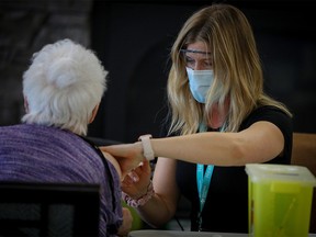 Stacey Israelson, RN, gives a COVID-19 vaccine to a resident at Aspen Ridge Lodge Seniors’ Housing in Didsbury, Alberta.