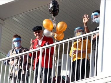 Retired RCMP S/Sgt. Arthur Levins is seen celebrating his 100th birthday. Family, friends and fellow RCMP officers gathered to wish Levins a happy birthday this afternoon. Around 40 cars drove past the Auburn Heights Seniors Residence hooking their horns with flags and home-made signs as Levins watched with healthcare workers by his side from his balcony. Saturday, November 28, 2020. Brendan Miller/Postmedia