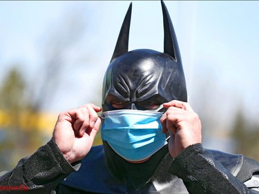 The character Holybatman puts on a surgical mask as he makes a visit outside the Children's Hospital in Calgary on Friday, May 15, 2020. He said it was his first time out in the warmer weather. 
Jim Wells/Postmedia