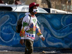 A man wearing a colourful sweater and a mask is seen walking down 17th Ave. SW. Friday, March 12, 2021.