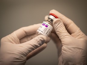 A pharmacist holds a vial of the AstraZeneca/Oxford COVID-19 vaccine in a pharmacy in Nantes, western France on March 25, 2021.