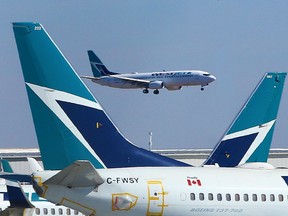 The tails of stored WestJet Boeing 737 planes frame another 737 as it lands at the Calgary International airport on Tuesday, March 23, 2021.