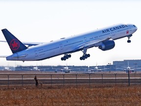 An Air Canada Boeing 777 takes off at the Calgary International Airport while WestJet Boeing 737 are lined up in storage in the distance on Tuesday, March 23, 2021.