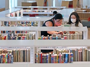 Elise Ferraro and her daughter Claire wear masks as they browse for books in the Central Library on Monday, July 27, 2020.