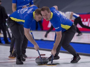 Alberta second Brad Thiessen (left) and Karrick Martin sweep during their victory against Wild Card 3 at the the Tim Hortons Brier at the Markin MacPhail Centre in Calgary on Monday, March 8, 2021.