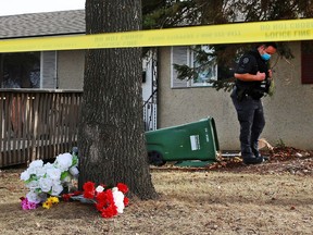 A memorial marks the scene as police forensics officers search the area where a man was fatally shot in the 5200 block of Memorial Drive S.E. on Saturday, March 27, 2021.