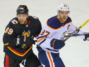 The Calgary Flames’ Nikita Nesterov gets tied up with the Edmonton Oilers’ Connor McDavid at the Saddledome in Calgary on Saturday, Feb. 6, 2021.