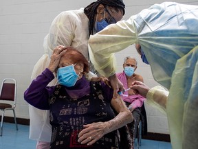 Nurses administer a COVID-19 vaccine to Maria DiStefano as her husband Vince DiStefano looks on, at St. Fidelis Parish in Toronto on March 17, 2021.