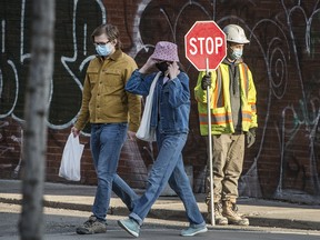 Pedestrians walk past a construction worker on Toronto’s Spadina Avenue on  March 3, 2021.