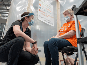 A doctor speaks with a patient on Monday during a demonstration of a mass vaccination clinic in Cobourg, Ont.
