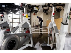 YEG Cycle Spin Studios' Grady Topak is framed by stationary bikes as he cleans up following a press conference where representatives of Alberta's fitness industry called on the government to further loosen COVID-19 gym restrictions, in Edmonton Wednesday March 10, 2021.