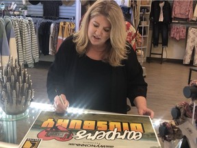 Karen Duggan, owner of Ulla La Boutique, with a sign business owners are putting in their windows in Didsbury to support Wynonna Earp and push for a fifth season. Ella La Boutique plays "Shorty's" in the series, which is partially filmed in Didsbury. Courtesy, Keep Alberta Rolling