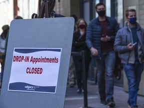 People who have booked an appointment wait in line to receive their COVID-19 vaccination as the drop-ip appointments have been closed at the immunization clinic at Telus Convention Centre on Tuesday, April 20, 2021.