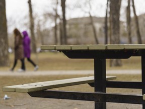 Two people walk through Pearce Estate Park in Calgary on Saturday, April 10, 2021. A Calgary councillor is looking to revive plans for a pilot project that would allow people to book picnic tables and enjoy a glass of beer or wine.