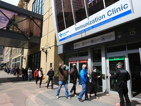 People line up as they wait to get immunized at the large COVID-19 vaccination site at the Telus Convention Centre on Monday, April 12, 2021.