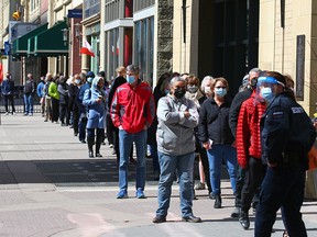 Calgarians line up as they wait to get immunized at the large COVID-19 vaccination site at the Telus Convention Centre on Monday, April 12, 2021.