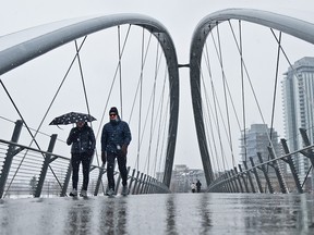 It was a snowy spring day in Calgary as pedestrians walk through flurries on the George C. King Bridge on Sunday, April 25, 2021.