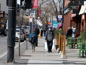 Masked pedestrians are seen walking along 17th Ave SW. Friday, April 2, 2021.