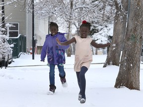 Seven year-old Abuk Garng (L) and her best friend six year-old Arek Kuot are seen embracing the winter weather in front of their home along 8th Ave. SW. Sunday, April 18, 2021.