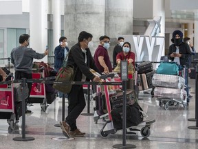 Passengers from Air India flight 187 from New Delhi wait for their transportation to quarantine after arriving at Pearson Airport in Toronto on Wednesday, April 21.