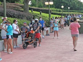 Guests wearing protective masks wait to pick up their tickets at the Magic Kingdom theme park at Walt Disney World on the first day of reopening, in Orlando, Florida, on July 11, 2020. A man was arrested for trespassing after he walked into the park without taking a temperature check.