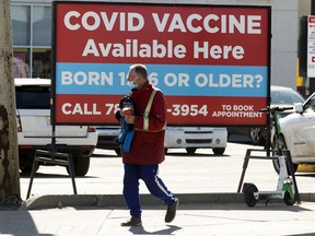 A pedestrian walks past a sign advertising COVID-19 vaccines at the Shoppers Drug Mart, 8065 104 St., in Edmonton Wednesday April 21, 2021. Photo by David Bloom