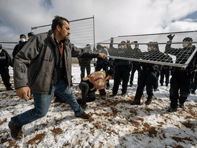 Police struggle with protesters trying to tear down a fence outside GraceLife Church near Edmonton on Sunday, April 11, 2021. The church has been fenced off for repeated violations of COVID-19 rules.