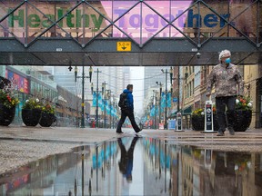 People walk into the COVID-19 vaccination clinic at the Telus Convention Centre on a cool morning, Thursday, April 22, 2021.