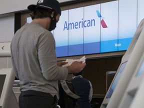A traveller wearing a protective mask checks a boarding pass after checking in at the American Airlines Group Inc. check-in counter at San Francisco International Airport (SFO) in San Francisco, California, U.S., on Wednesday, July 1, 2020.