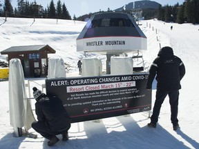 Staff put up a sign at the base of Whistler Mountain in Whistler, B.C., on March 15, 2020. The Whistler Blackcomb resort is battling a COVID-19 outbreak.