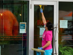 A worker in a COVID-19 mask cleans the windows of Rëdl Kitchen on 124 Street in Edmonton on Friday, May 28, 2021.