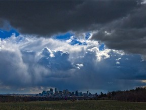 Storm clouds move in over walkers in Edworthy Park and the downtown Calgary skyline on Tuesday, May 4, 2021.