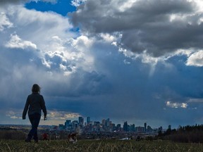 Storm clouds move in over walkers in Edworthy Park and the downtown Calgary skyline on May 4, 2021.